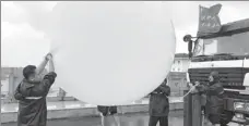  ?? YANG YANG / FOR CHINA DAILY ?? Right below: Scientists release balloons on Zhujiajian Island, Zhejiang, carrying apparatus to collect accurate data from the typhoon.