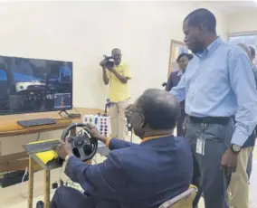  ?? ?? United States Ambassador to Jamaica N Nick Perry is guided by NCU instructor Earlando Tracey in using an articulate­d truck-driving simulator.