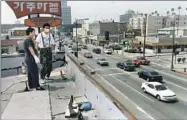  ?? Hyungwon Kang Los Angeles Times ?? EMPLOYEES of California Market and armed Korean Americans guard the grocery from its roof in May 1992.