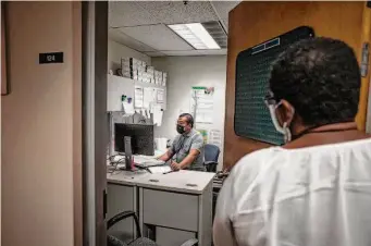  ?? Larry Valenzuela/CalMatters ?? Fresno County communicab­le disease specialist Hou Vang works in his office as program manager Jena Adams checks in. They are trying to quell the spread of syphilis in the Central Valley.