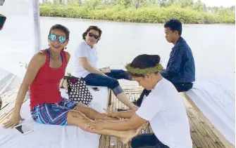  ??  ?? Footnote: Dyan Castillejo and Susan Afan get a foot massage by the quiet river in Dulag, Leyte.