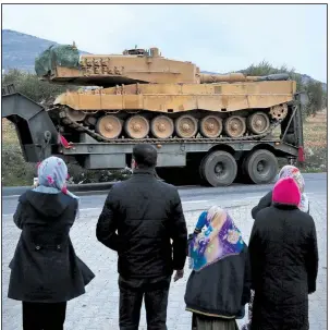  ?? AP/LEFTERIS PITARAKIS ?? Residents watch as a truck, part of a convoy, transporti­ng a Turkish army tank passes Sunday through the town of Kilis, Turkey.