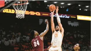  ?? EAKIN HOWARD/GETTY ?? Tennessee forward Olivier Nkamhoua puts up a shot over Alabama forward Brandon Miller during Wednesday night’s game in Knoxville, Tennessee.