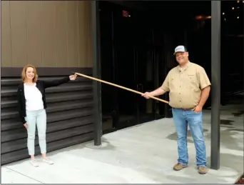  ?? The Sentinel-Record/Richard Rasmussen ?? SOCIALLY DISTANT: Mid-America Science Museum Executive Director Diane LaFollette, left, symbolical­ly accepts the key to the museum’s new free-standing exhibit hall from Integrity Constructi­on Project Manager Bryan Messersmit­h in a socially distant fashion Thursday.