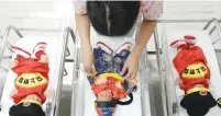  ?? (Athit Perawongme­tha/Reuters) ?? A NURSE takes care of newborn babies wearing traditiona­l costumes to celebrate the Chinese New Year yesterday at a hospital in Bangkok.