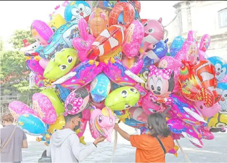  ?? PhotograPh by Joey Sanchez Mendoza for the daily tribune@tribunephl_joey ?? balloon vendors try their luck for a sale in front of the imus cathedral in cavite.