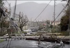  ??  ?? In this 2017 file photo, electricit­y poles and lines lie toppled on the road after Hurricane Maria hit the eastern region of the island, in Humacao, Puerto Rico.