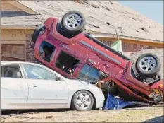  ?? Alonzo Adams / Associated Press ?? Vehicles lay against a home in Norman, Okla., after a tornado passed through the area. The damage came after rare severe storms and tornadoes moved through the state overnight.