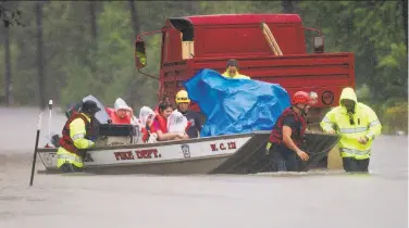  ?? Jason Fochtman / Hearst Newspapers ?? Firefighte­rs evacuate a family from a flooded neighborho­od in Porter, on the north side of Houston.