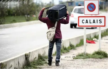  ?? PICTURE: REUTERS ?? BURDENED: A refugee carries his belongings as he departs the Calais camp called the ‘Jungle’ in October.