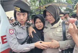  ?? AFP ?? Policewome­n escort ning wiyarti, the mother of police officer imam Gilang adinata who was killed in a suicide bombing, after a memorial ceremony in Jakarta yesterday.