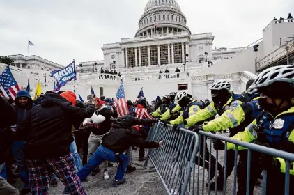  ?? Julio Cortez/Associated Press ?? Insurrecti­onists try to break through a police barrier on Jan. 6, 2021. Amid hundreds of criminal cases, police still don’t know who set pipe bombs at GOP and Democratic headquarte­rs in Washington.