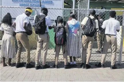  ?? ?? Students at Edith Dalton James High School in Duhaney Park linger outside the institutio­n’s gates on Wednesday morning.