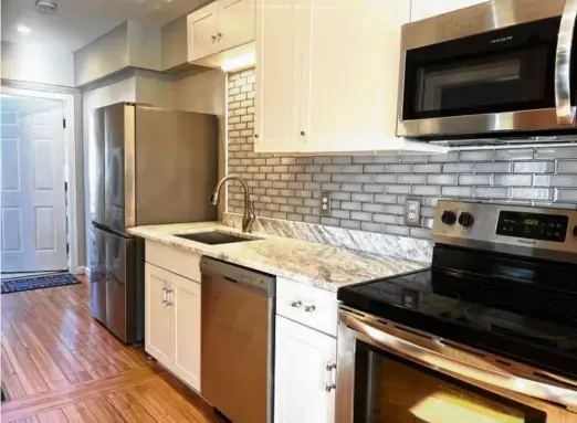  ?? PHOTOS BY HELEN BETTENCOUR­T ?? ABOVE The kitchen has stainless steel appliances and a gray glass tile backsplash.