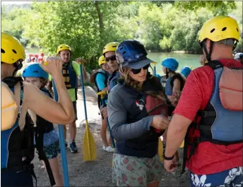  ?? ?? Hanah Webster of Mountain Waters Rafting checks the fit of personal flotation devices for members of the Hartford family, who were headed out on a rafting trip while visiting Durango, as they prepare to go down the Animas River on July 14.