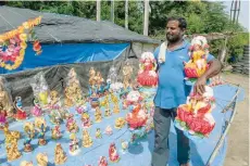  ?? — AFP ?? An artist carries statues of goddess Lakshmi to display for sale at a roadside stall ahead of the Diwali festival in Hyderabad.