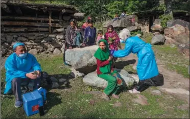  ??  ?? Farid (right) administer­s a dose of Covishield vaccine to Meema Begum, a Kashmiri shepherd woman, as others watch June 22 during a covid-19 vaccinatio­n drive in Gagangeer.