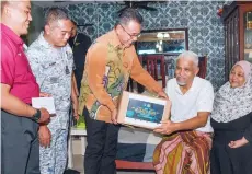  ?? — Bernama photo ?? Adly (centre) presenting contributi­on to Safaruddin (second right) at Taman Semarak in Kajang.