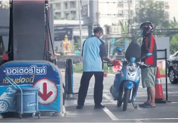  ?? WICHAN CHAROENKIA­TPAKUL ?? An attendant refuels a motorbike at a petrol station. Reducing gasohol costs by 250 baht per month for 157,000 registered motorcycle drivers is one measure to alleviate hardships for low-income earners.