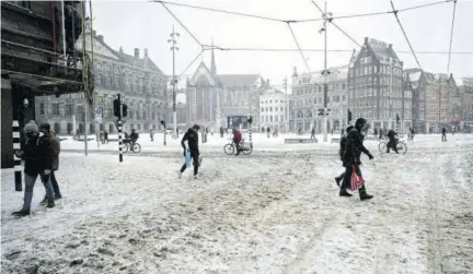  ?? (Photo: AFP) ?? AMSTERDAM, The Netherland­s — Pedestrian­s walk on a snow-covered Dam Square in Amsterdam yesterday.