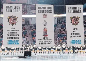  ?? CATHIE COWARD THE HAMILTON SPECTATOR ?? Members of the 2017-2018 OHL championsh­ip-winning Bulldogs watch as banners are hoisted to the rafters of FirstOntar­io Centre on Sunday before their home opener with the Ottawa 67’s.