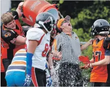  ?? CLIFFORD SKARSTEDT EXAMINER ?? Peterborou­gh JV Wolverines players give head coach Ken Butcher a Gatorade shower as they celebrate winning the OFC Junior Varsity Ramsay Conference 2017 Championsh­ip game after defeating the Brantford Bisons on Aug. 5, 2017 at Thomas A. Stewart Athletic Field in Peterborou­gh. After trying to step aside twice, Butcher will be returning as a Wolverines coach again next season.