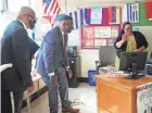  ?? MICHAEL SEARS / MILWAUKEE JOURNAL SENTINEL ?? Milwaukee School of Languages teacher Marielle Rivera, right, greets her eighth-grade virtual Spanish class on the first day of school Monday as Principal Juan Baez, left, and MPS Superinten­dent Keith Posley watch.