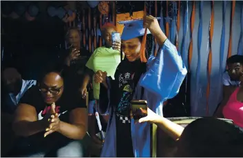  ?? JESSIE WARDARSKI — THE ASSOCIATED PRESS ?? Sharawn Vinson, front left, family members and friends cheer for her daughter, Maddison, as they watch her virtual graduation from middle school in the living room of their three-bedroom apartment in the Brooklyn.