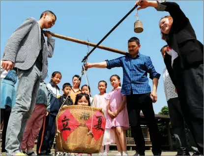  ?? HU JIANHUAN / FOR CHINA DAILY ?? Kids experience getting weighed on lixia, Start of Summer, in Hangzhou, Zhejiang province.
