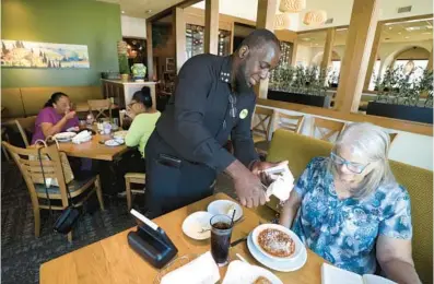  ?? ?? Olive Garden server Christophe­r Johnson adds cheese to Becky Hartwig’s soup on May 16. Hartwig is one of Johnson’s regular customers.