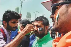  ?? Virendra Saklani/Gulf News ?? Indian and Pakistani fans get the flags of their countries painted on their faces before the much-awaited encounter.