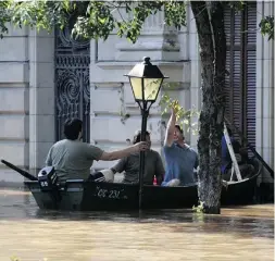  ?? MILTON CABRERA / AFP / Getty Images ?? Men on a boat during floods in Paysandu, Uruguay. More than 170,000 people have been driven from their homes in Paraguay, Argentina, Brazil and Uruguay in severe flooding.