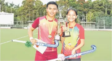  ??  ?? Sarawak school hockey championsh­ip Best Player Award winners M Haziq Asyraaf Berahim and Elizabeth Epui Martin shows off their trophies after the finals at the Sarawak Hockey Stadium.