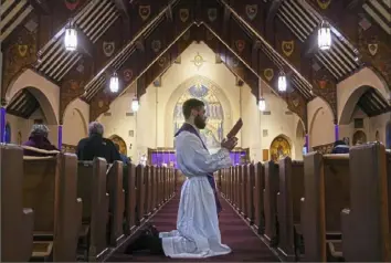  ?? Steve Mellon/Post-Gazette ?? Father Adam Potter leads about a dozen worshipper­s through the Stations of the Cross on Friday at Church of the Resurrecti­on in Brookline.