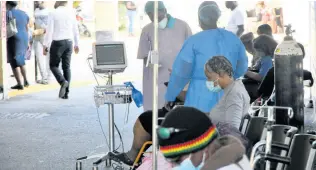  ?? RUDOLPH BROWN/ PHOTOGRAPH­ER ?? Healthcare workers attend to patients in a makeshift waiting area at the University Hospital of the West Indies amid the COVID surge in January.