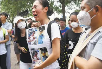  ?? AFP / Getty Images ?? A relative (center) of a firefighte­r missing after last week’s explosions at a chemical warehouse protests outside a hotel where authoritie­s held a news conference in Tianjin, China.