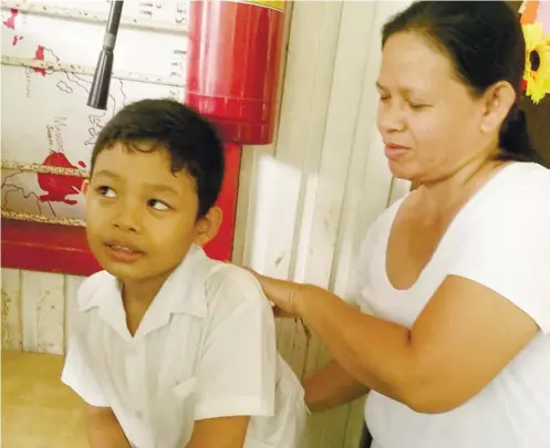  ?? SUNSTAR FOTO / ALEX BADAYOS ?? SURVIVOR. Aquilisa Ngalot attends to her son, Fritz, while at school. Fritz, 10, fell ill with dengue this year, less than a week after a 6-year-old neighbor died of the viral infection. Fritz received treatment in a private hospital. When caught...