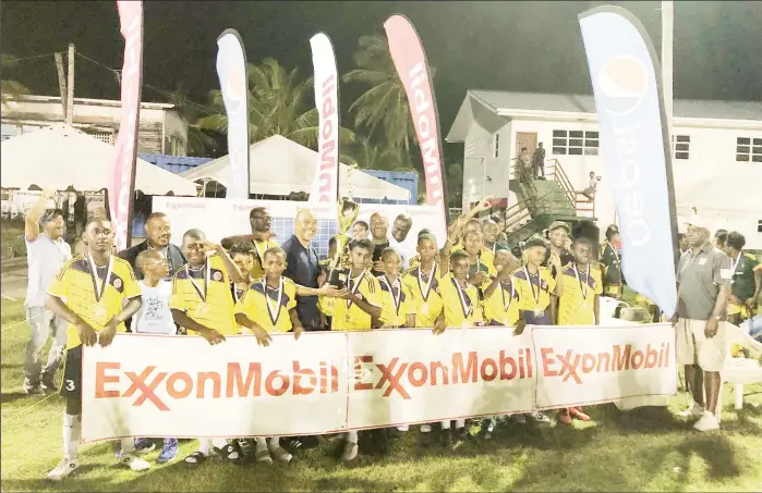  ?? ?? Marcus Tripp, Senior Director of Government and Public Affairs of ExxonMobil, presents the championsh­ip trophy to Charlestow­n captain Malcolm Hendricks in the presence of teammates, sponsors, and tournament officials