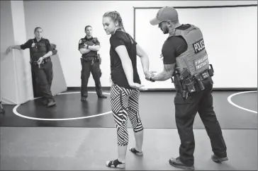  ?? Herald photo by Tijana Martin ?? Const. Jonathan Brunning used volunteer Kara Smith, from Chinook High School, to demonstrat­e how to properly handcuff someone during the second annual Youth Academy at LPS Headquarte­rs on Friday. @TMartinHer­ald