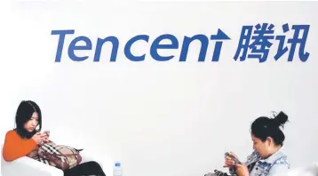  ??  ?? Visitors use their smartphone­s underneath the logo of Tencent at the Global Mobile Internet Conference in Beijing. Tencent Music, which owns China’s most popular music apps, has filed for a US IPO seeking funds to develop content and new services, in what is expected to be one of the biggest US listings by a Chinese company this year. — Reuters file photo