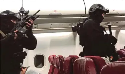  ??  ?? Heavily-armed police officers making their way through the cabin of Malaysia Airlines Flight MH128.