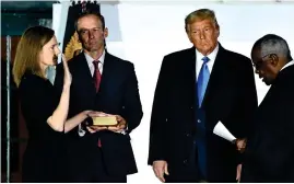  ?? AFP ?? Donald Trump looks on as Supreme Court Associate Justice Clarence Thomas administer­s the oath to Judge Amy Coney Barrett as a US Supreme Court Associate Justice, flanked by her husband Jesse M. Barrett at the White House in Washington, DC. —