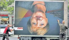  ?? REUTERS ?? (Left) Workers remove an election campaign billboard showing German Chancellor Angela Merkel’s face, which has been vandalised with a Hitleresqu­e moustache; (right) AfD coleader Frauke Petry storms out after quitting the party.