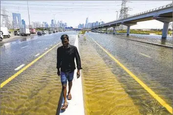  ?? Christophe­r Pike Associated Press ?? A MAN walks along a f looded road in Dubai. By the end of Tuesday, more than 5.59 inches of rainfall had soaked Dubai over 24 hours. An average year brings 3.73 inches of rain to Dubai Internatio­nal Airport.