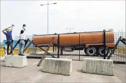  ?? Fernando Vergara The Associated Press ?? Journalist­s record a fuel tanker, cargo trailers and makeshift fencing used as barricades by Venezuelan authoritie­s attempting to block humanitari­an aid on the Tienditas Internatio­nal Bridge on Wednesday on the outskirts of Cucuta, Colombia.