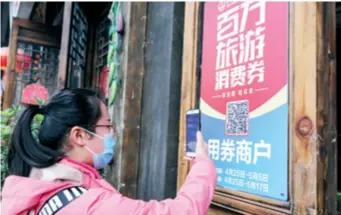  ??  ?? A tourist scans the QR code to pick up a consumptio­n voucher in a county in southwest China’s Guizhou Province on April 25