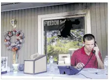  ?? JONATHAN DREW / AP ?? Blake Halsey takes a call Monday at the Orange County Republican office in Hillsborou­gh, N.C. Behind him is the window through which authoritie­s say someone threw a flammable device.