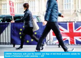  ??  ?? LONDON: Pedestrian­s walk past the banners and flags of Anti-Brexit protesters outside the Houses of Parliament in London yesterday. — AFP