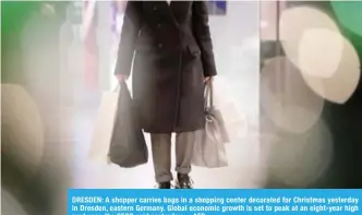  ??  ?? DRESDEN: A shopper carries bags in a shopping center decorated for Christmas yesterday in Dresden, eastern Germany. Global economic growth is set to peak at an eight-year high next year, the OECD said yesterday. —AFP