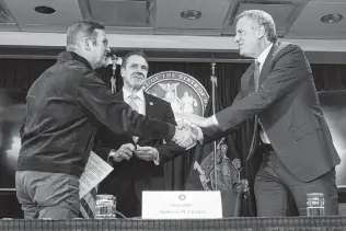  ?? Chang W. Lee / New York Times ?? John Schoettler, Amazon's vice president for global real estate and facilities, left, New York Gov. Andrew Cuomo and Mayor Bill de Blasio meet Tuesday to announce Amazon’s plan.